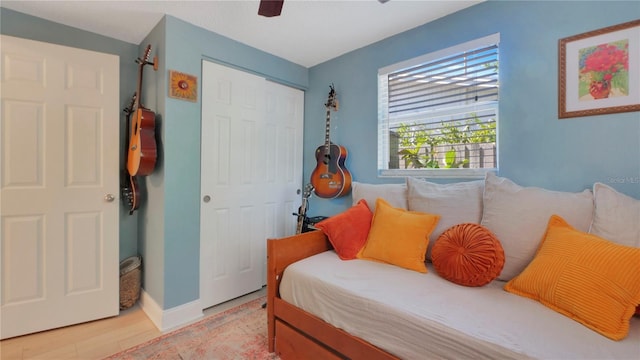 bedroom featuring ceiling fan, light wood finished floors, a closet, and baseboards