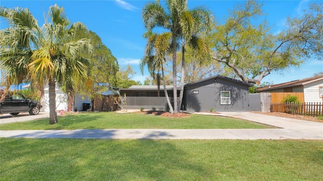 view of front of house with a front yard, concrete driveway, and fence