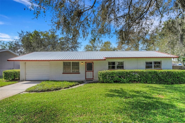 ranch-style home featuring metal roof, an attached garage, brick siding, concrete driveway, and a front lawn