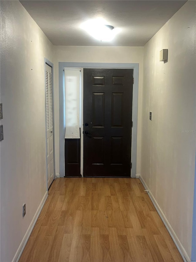 doorway to outside featuring baseboards and light wood-type flooring