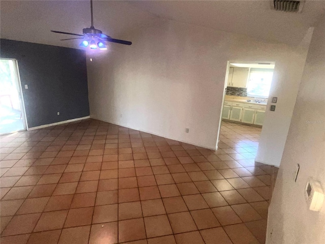 empty room featuring light tile patterned flooring, visible vents, ceiling fan, and lofted ceiling