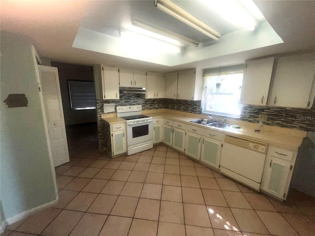 kitchen with white appliances, light countertops, under cabinet range hood, and a sink