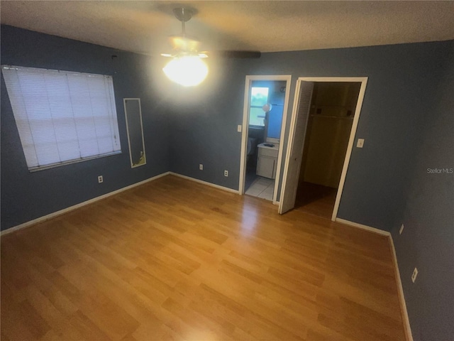 empty room with light wood-style flooring, a ceiling fan, and baseboards