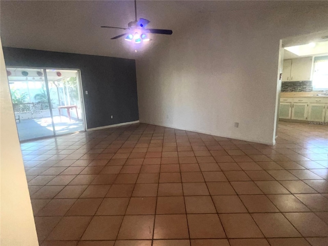 empty room with lofted ceiling, light tile patterned floors, and a ceiling fan