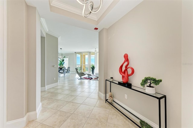 hall featuring light tile patterned floors, a raised ceiling, ornamental molding, a baseboard heating unit, and baseboards