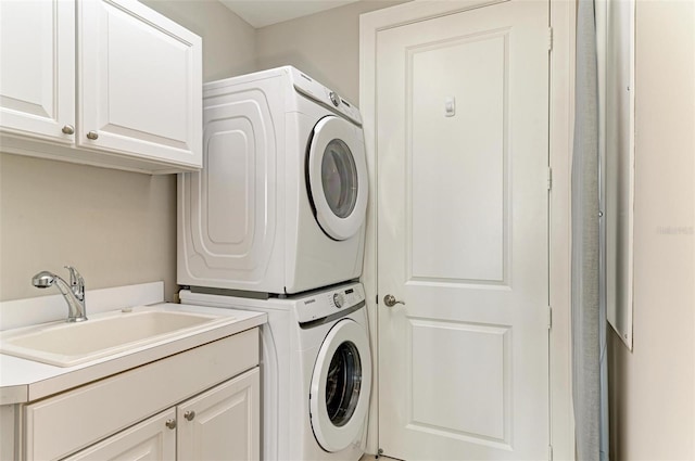 washroom with cabinet space, a sink, and stacked washing maching and dryer