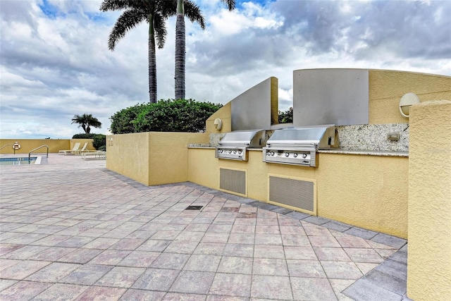 view of patio / terrace featuring a grill, a community pool, and an outdoor kitchen