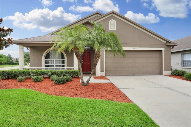 view of front facade featuring driveway, a front lawn, an attached garage, and stucco siding