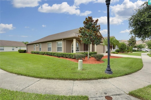 view of front of property with driveway, a front yard, an attached garage, and stucco siding