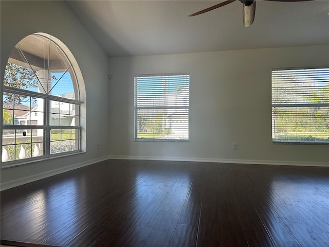 empty room with vaulted ceiling, dark wood-style flooring, a ceiling fan, and baseboards