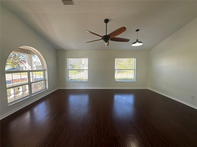 spare room featuring lofted ceiling, ceiling fan, visible vents, baseboards, and dark wood-style floors