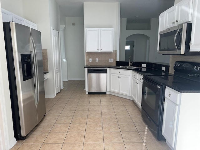 kitchen featuring dark countertops, light tile patterned floors, stainless steel appliances, and a sink