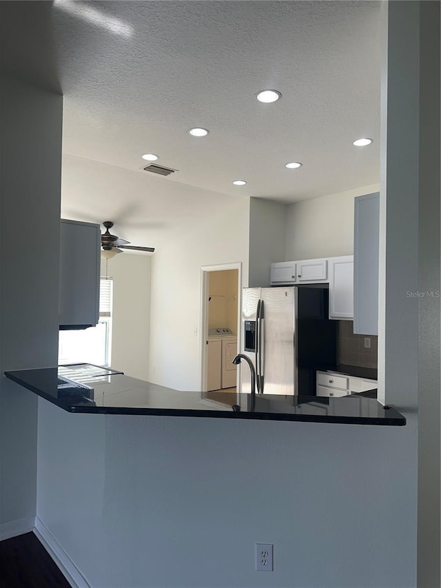 kitchen with a peninsula, separate washer and dryer, dark countertops, and stainless steel fridge