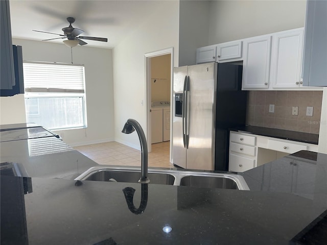 kitchen with tasteful backsplash, stainless steel fridge, washing machine and dryer, white cabinetry, and a sink