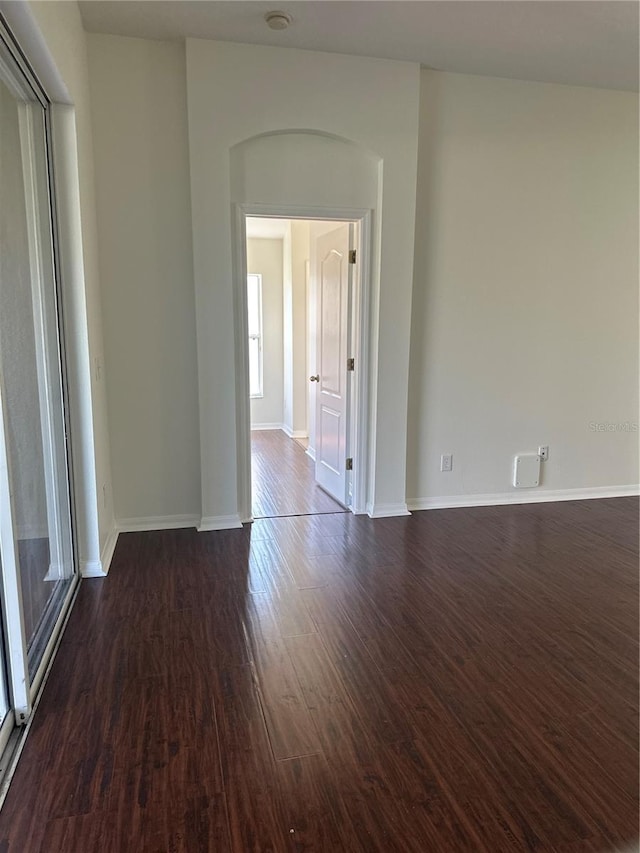 spare room featuring dark wood-style floors and baseboards