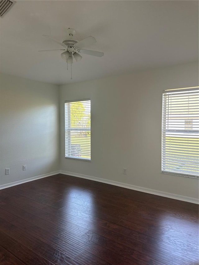 unfurnished room featuring a ceiling fan, baseboards, visible vents, and dark wood-type flooring