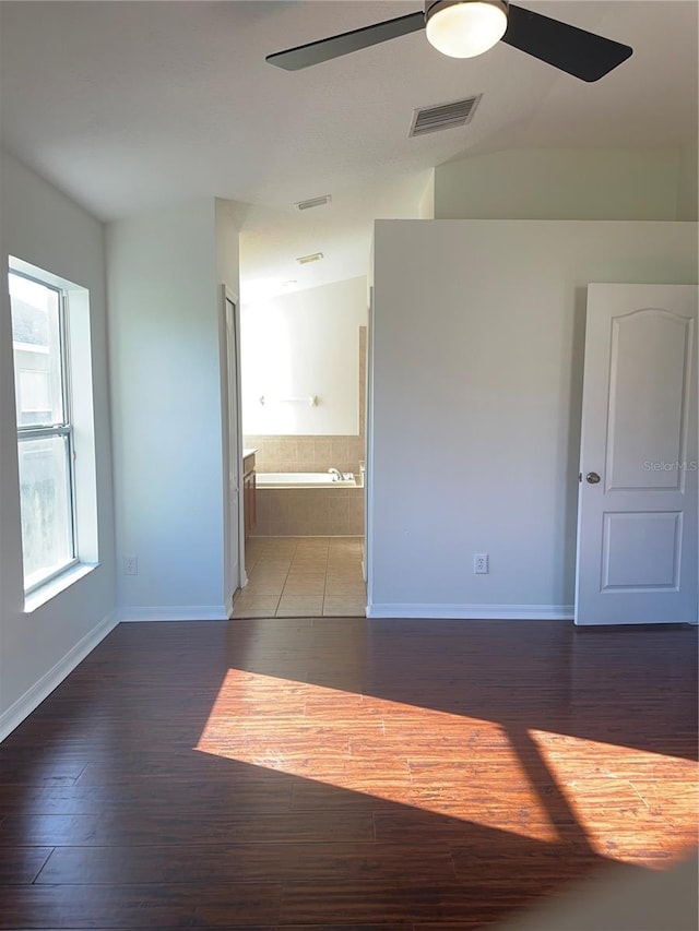 empty room with lofted ceiling, ceiling fan, wood finished floors, and visible vents