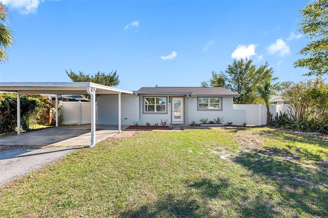 ranch-style home with an attached carport, fence, driveway, stucco siding, and a front yard