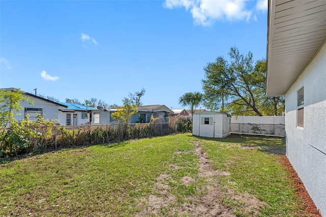 view of yard with a fenced backyard, an outdoor structure, and a storage unit