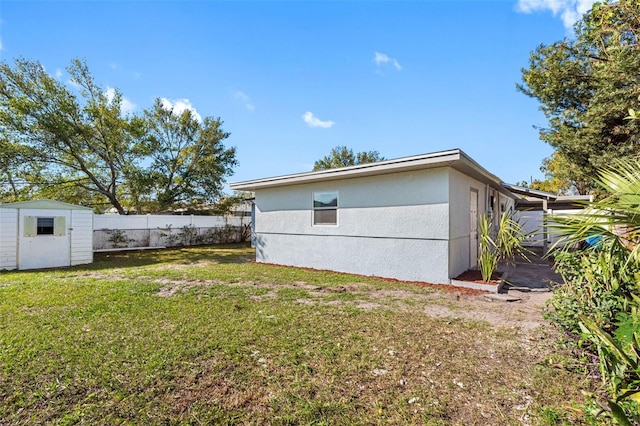 view of property exterior featuring a yard, fence, an outdoor structure, a shed, and stucco siding