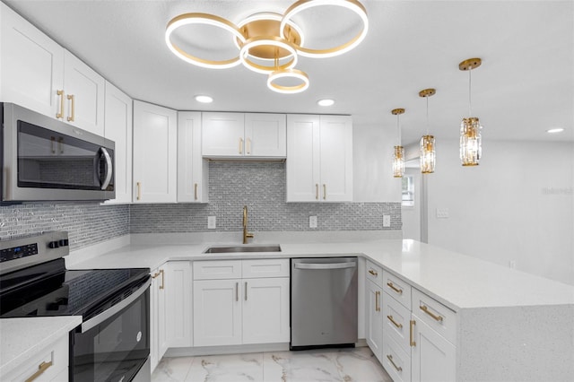 kitchen with marble finish floor, stainless steel appliances, decorative backsplash, a sink, and a peninsula