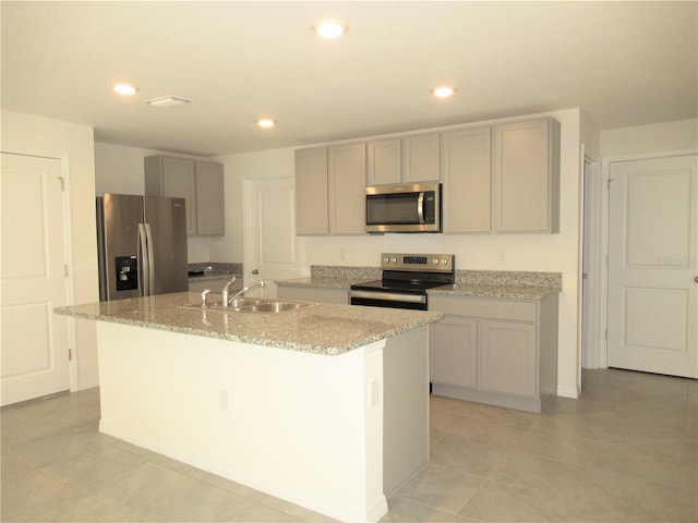 kitchen with a center island with sink, appliances with stainless steel finishes, gray cabinetry, a sink, and recessed lighting