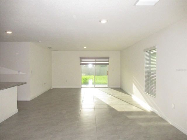 spare room featuring a healthy amount of sunlight, baseboards, visible vents, and recessed lighting