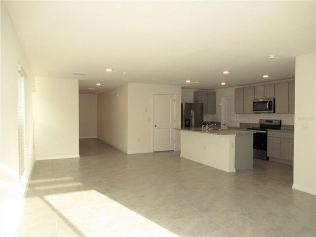 kitchen with a center island with sink, appliances with stainless steel finishes, open floor plan, a sink, and recessed lighting