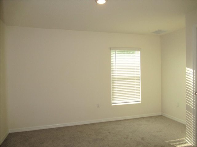 spare room featuring carpet floors, visible vents, and baseboards