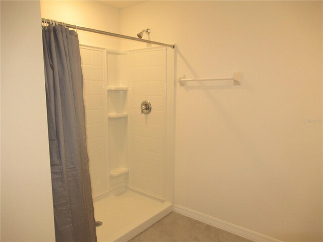 full bath featuring tile patterned floors, baseboards, and a shower with shower curtain