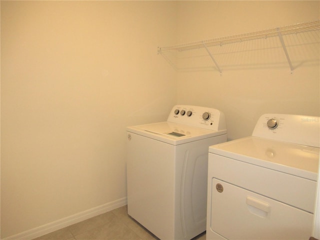 laundry room featuring laundry area, light tile patterned floors, baseboards, and washing machine and clothes dryer