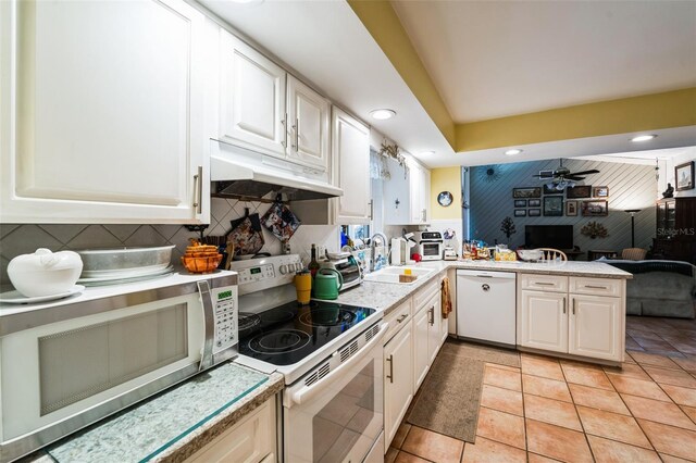 105 Country Club Ln, Mulberry, FL 33860 - kitchen featuring white appliances, a peninsula, a sink, light countertops, and under cabinet range hood