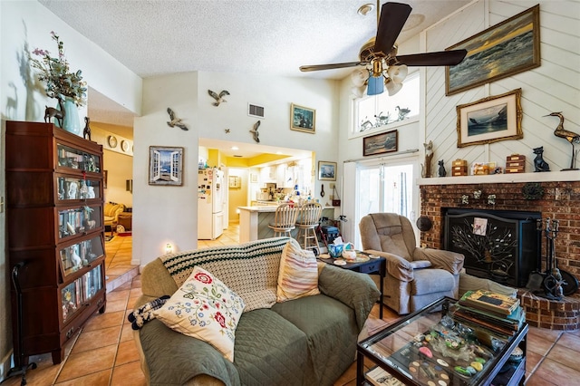 105 Country Club Ln, Mulberry, FL 33860 - tiled living room featuring visible vents, a ceiling fan, a textured ceiling, a high ceiling, and a brick fireplace