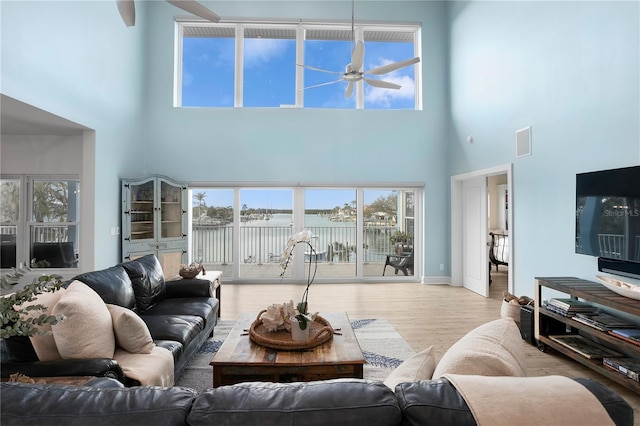 living area featuring baseboards, ceiling fan, visible vents, and wood finished floors