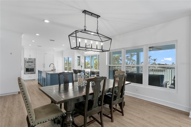 dining area with an inviting chandelier, light wood-style flooring, baseboards, and recessed lighting