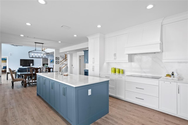 kitchen featuring custom range hood, white cabinetry, a sink, blue cabinets, and black electric cooktop