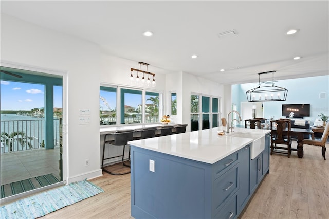 kitchen featuring light wood-type flooring, plenty of natural light, decorative light fixtures, and a sink