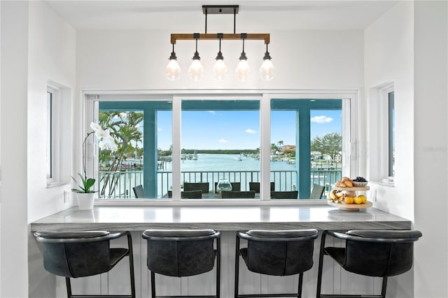 kitchen with a water view, a kitchen bar, and pendant lighting