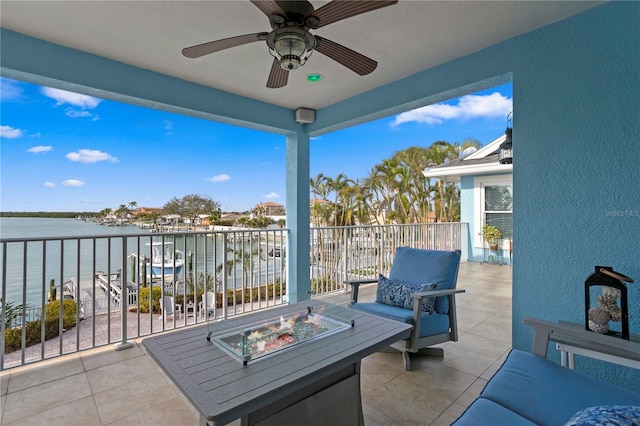 view of patio / terrace with a water view, an outdoor living space with a fire pit, and a ceiling fan