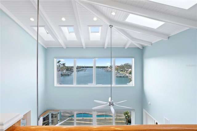 room details featuring beamed ceiling, a skylight, and a water view