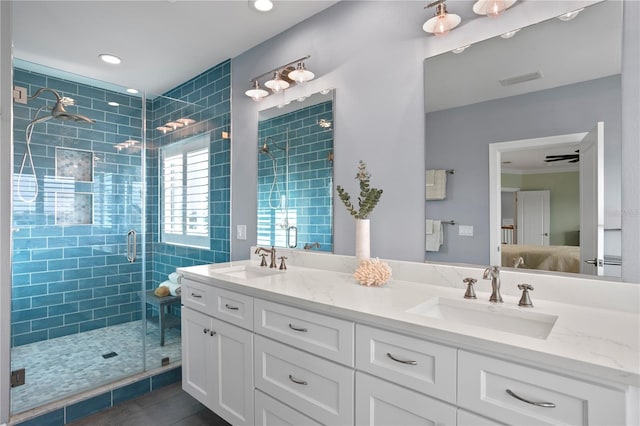 ensuite bathroom featuring connected bathroom, a stall shower, a sink, and double vanity