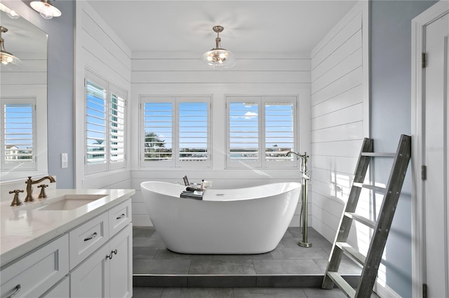 bathroom featuring tile patterned flooring, wood walls, a freestanding bath, and vanity