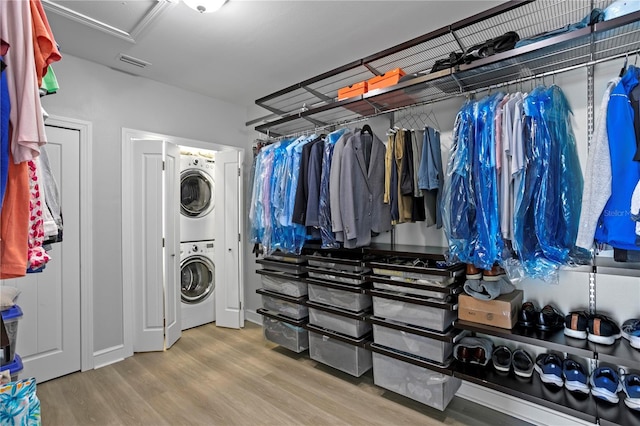 washroom with stacked washer / dryer, laundry area, visible vents, and wood finished floors