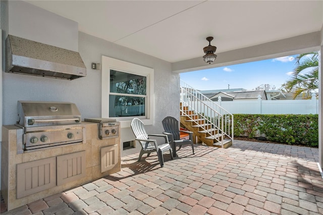 view of patio featuring stairs, a grill, an outdoor kitchen, and fence