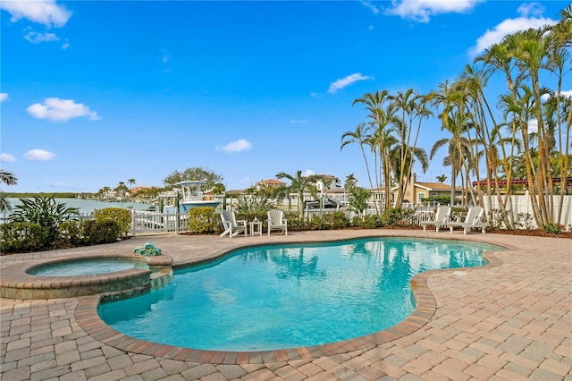 view of pool featuring a patio, fence, and a pool with connected hot tub