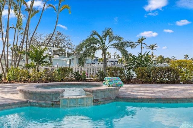 view of pool featuring fence and a pool with connected hot tub