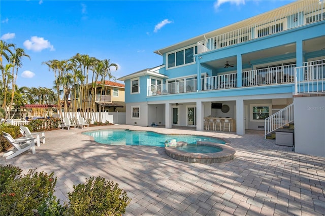 view of swimming pool featuring a patio, a pool with connected hot tub, ceiling fan, fence, and exterior kitchen