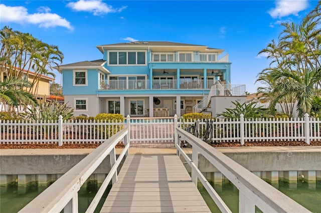 rear view of house featuring a fenced front yard, a fenced in pool, stucco siding, a balcony, and stairs