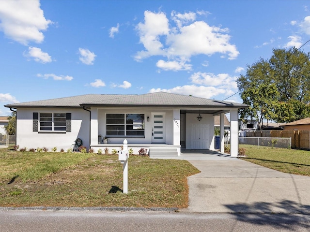 view of front of house with driveway, stucco siding, fence, and a front yard