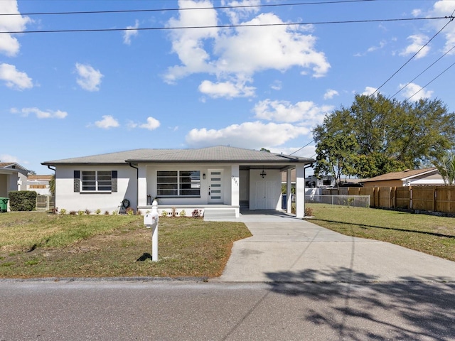 view of front of property with driveway, an attached carport, fence, a front lawn, and stucco siding